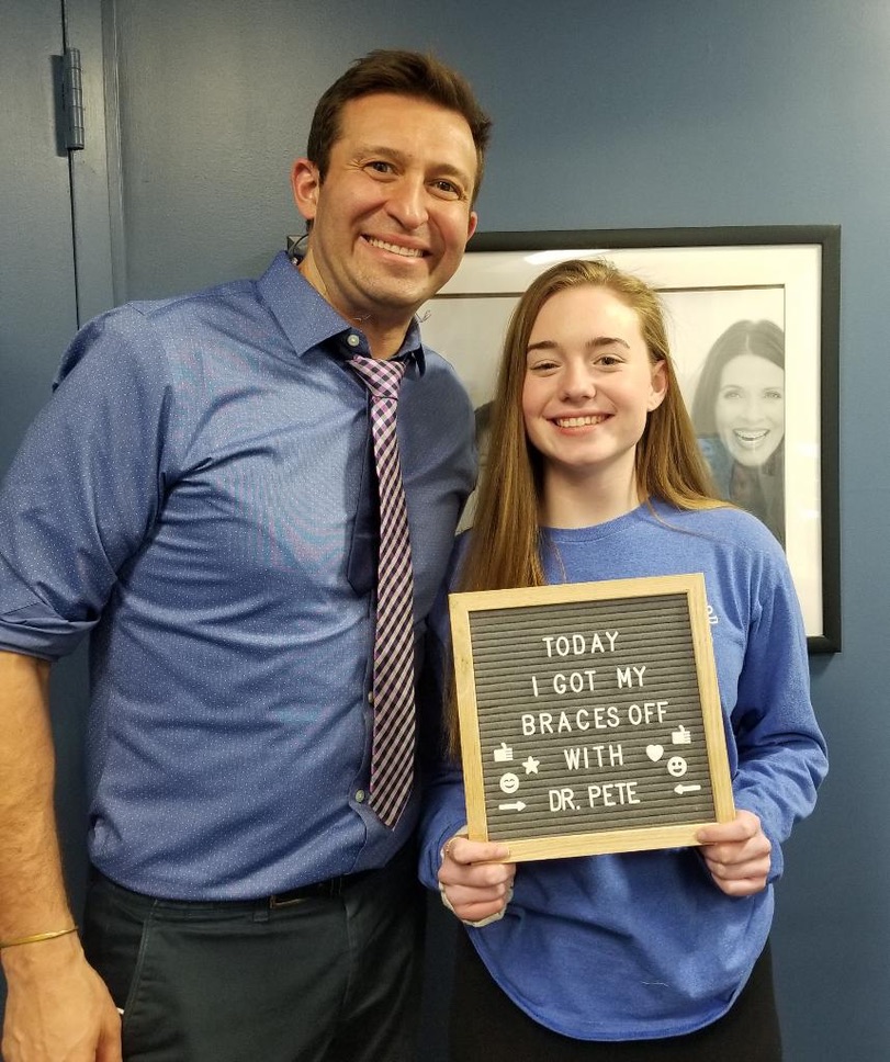 A Dental Care Orthodontics patient celebrating braces-off day with Dr. Peter Feibish